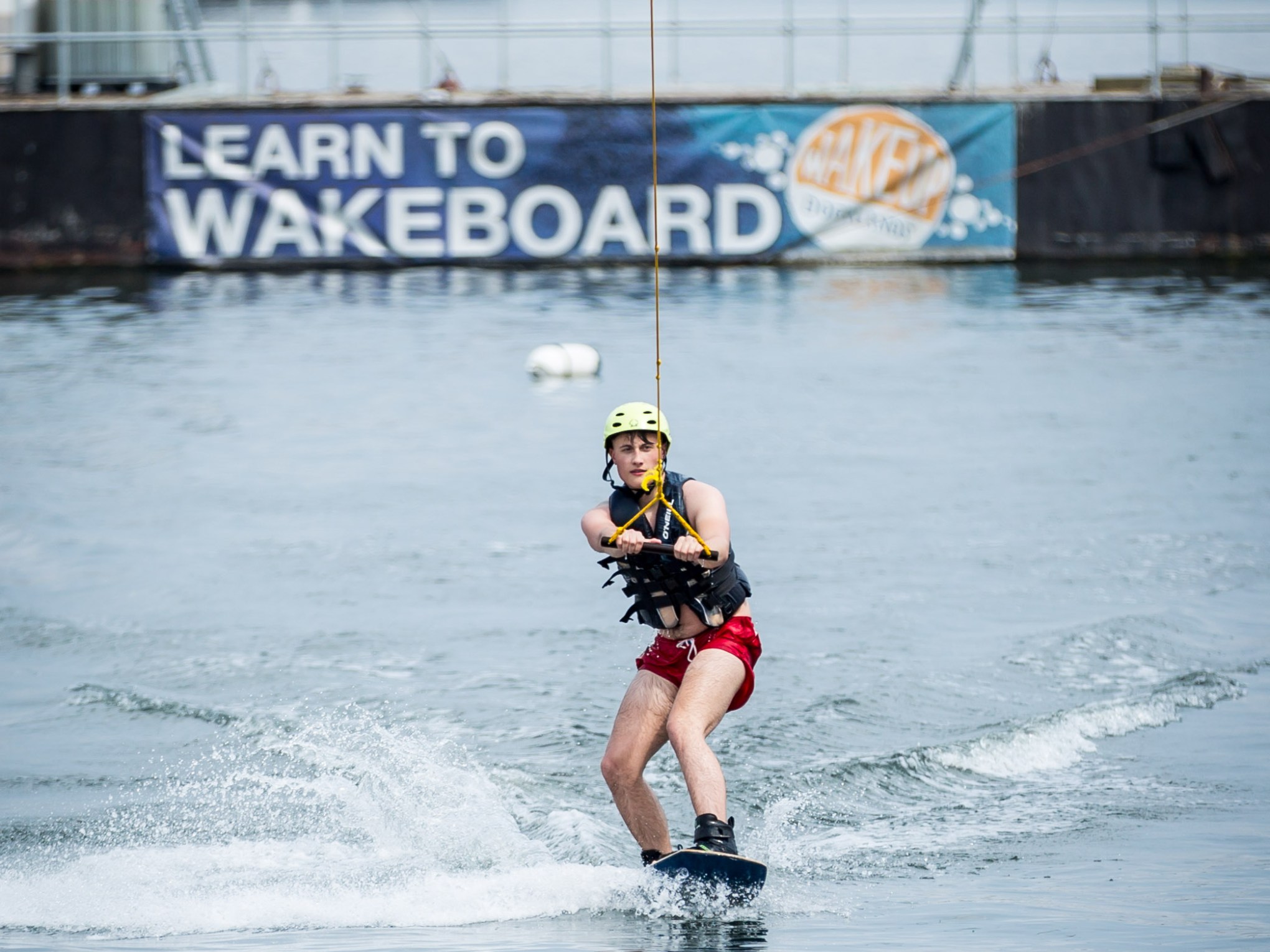 Person wakeboarding on a waterway wearing a helmet and vest.