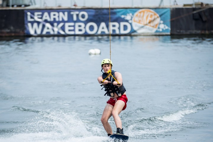 Person wakeboarding on a waterway wearing a helmet and vest.