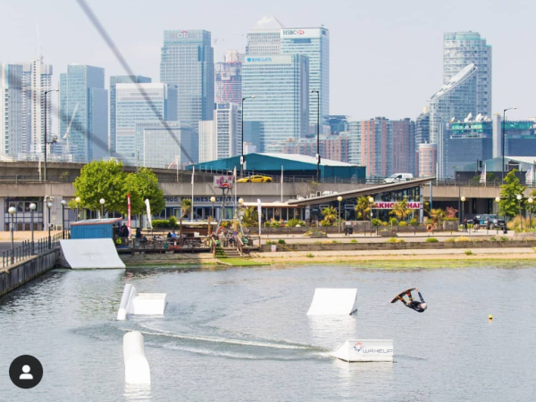 Person wakeboarding on a city river with skyscrapers in the background.