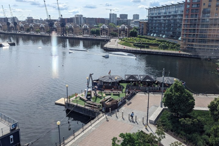 Riverside view with small park and people walking on a sunny day.