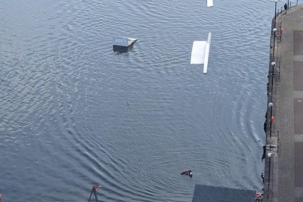 Aerial view of a river with floating platforms and a riverside construction area.