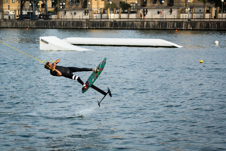 Person wakeboarding, mid-air in front of a water obstacle.
