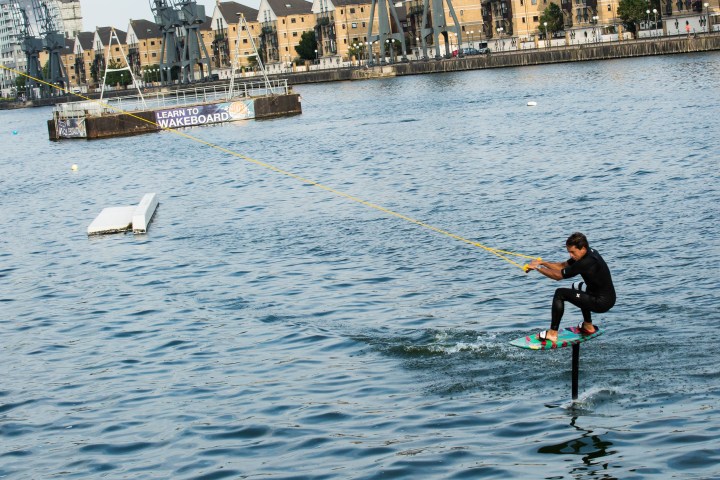 Person wakeboarding on a lake with a cityscape in the background.