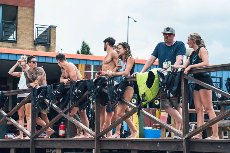 Group of people in swimwear standing by a wooden railing with life vests.